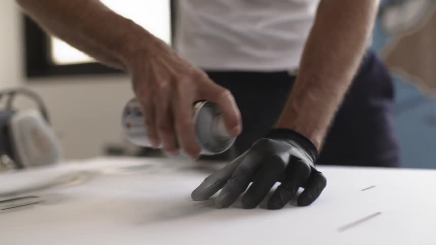 A man is spray painting while wearing a black glove