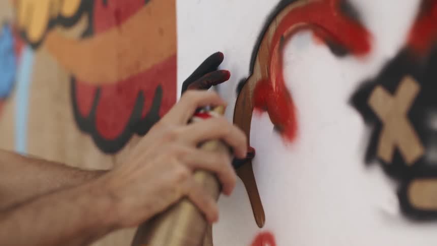 A man is spray painting a wall outdoors