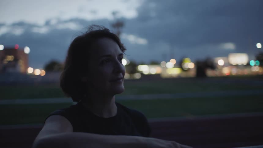 A woman is outside at night looking around