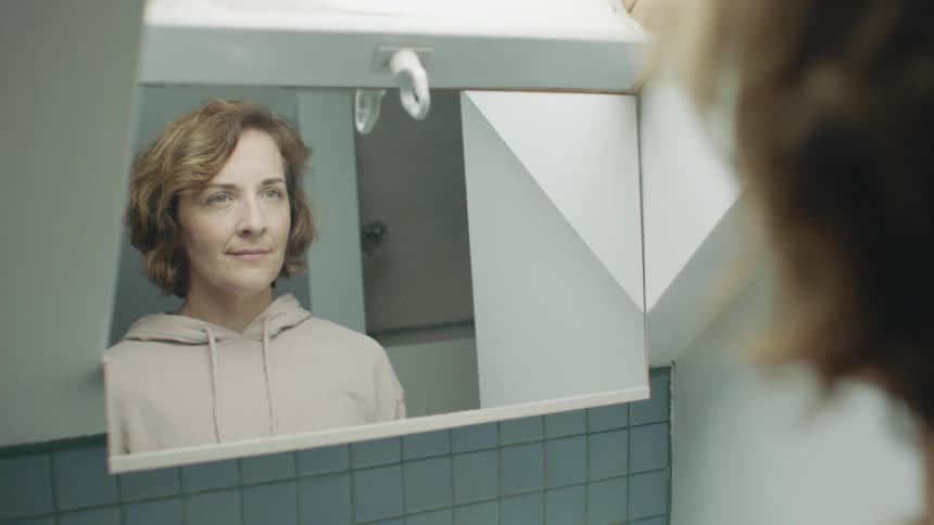 A woman is looking at a mirror and smiling