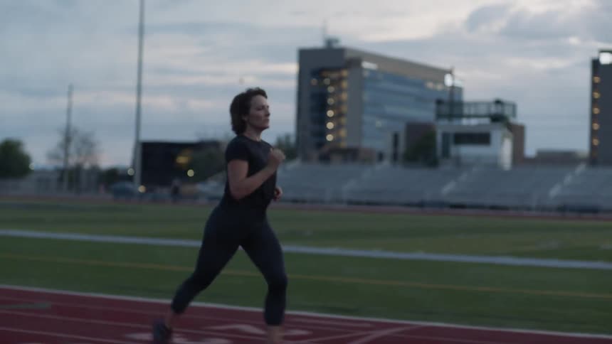 On a cloudy day a woman jogs on the track