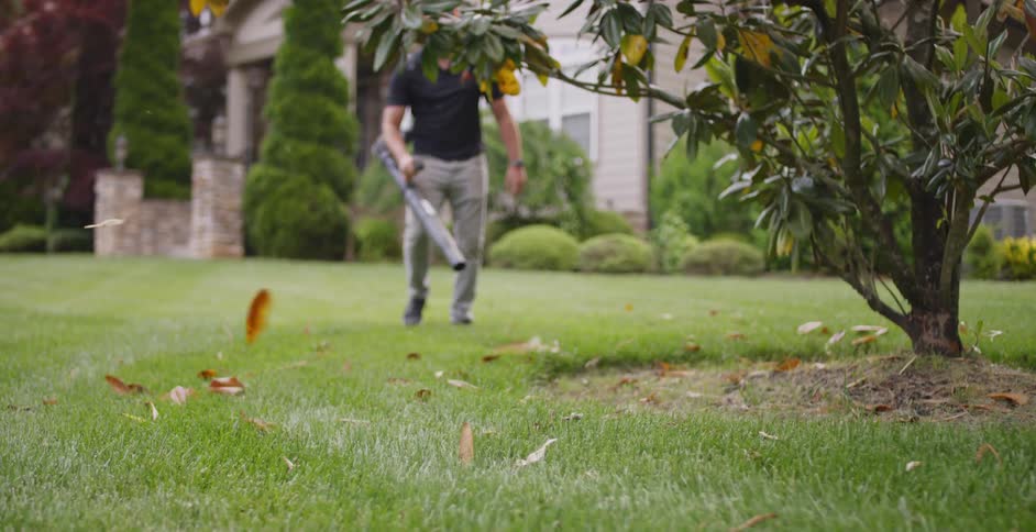 A man is using a leaf blower outdoors