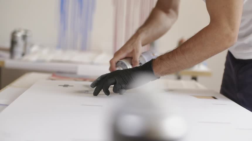 A man is using spray paint while wearing one glove