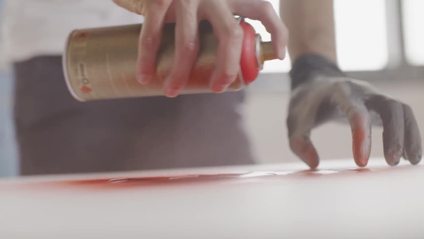 A man spray paints over a stencil