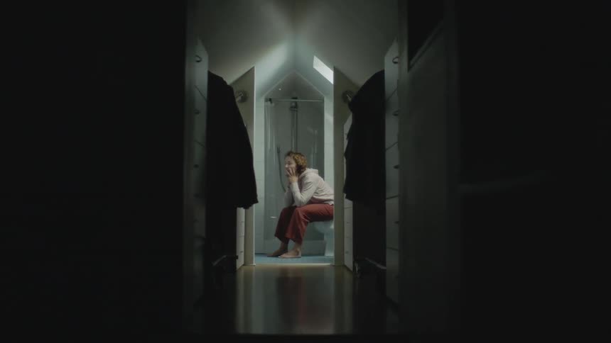 A worried woman sits on a toilet