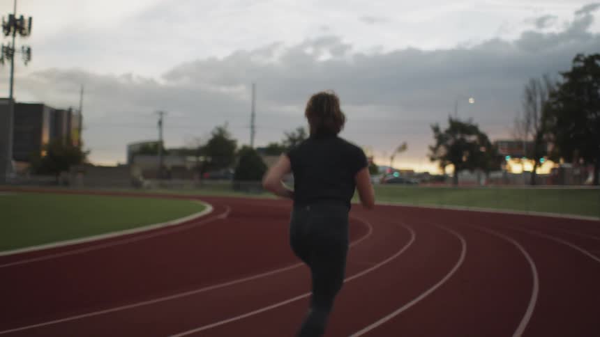 A woman runs around a track