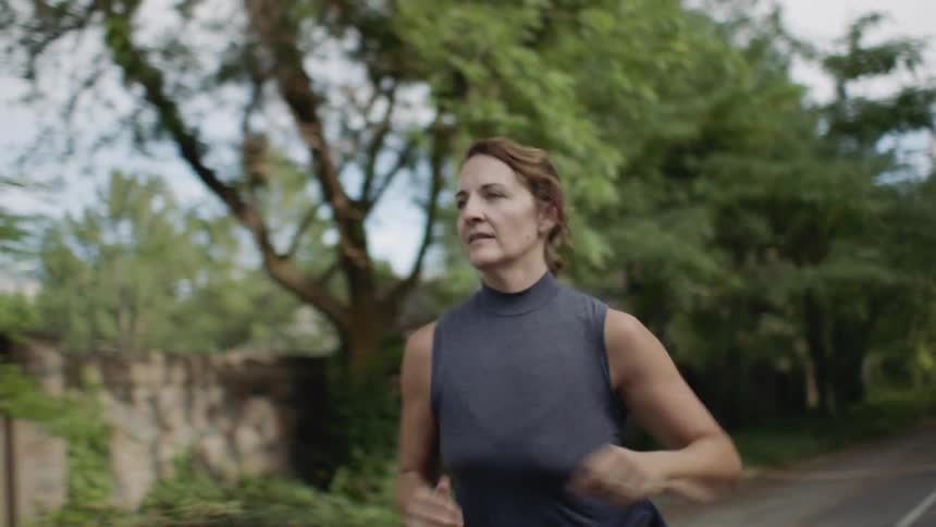 Woman jogs down the street at noon