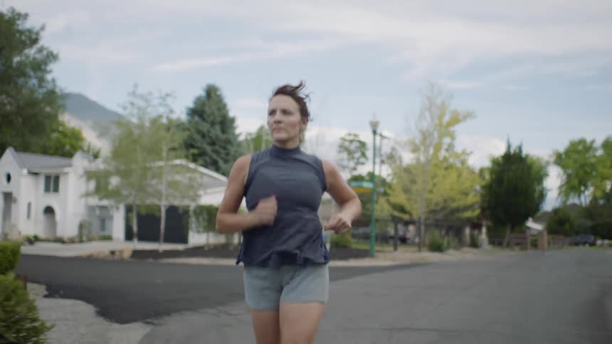 A woman jogging down a suburban street with large houses
