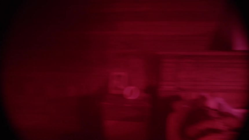 A man sleeping on a bed as the camera gets a red tint