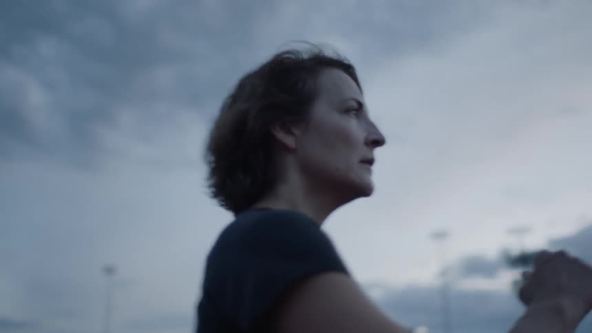 A woman power walks in a city at sunset