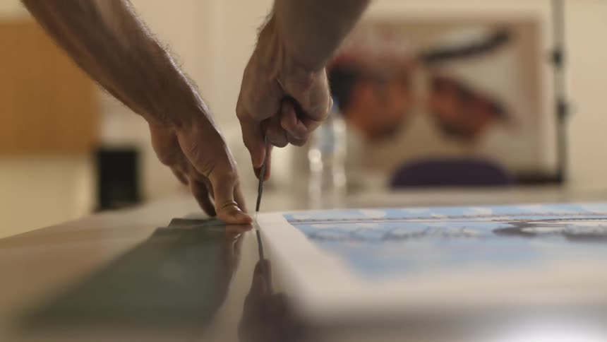A man cutting the edge of a canvas