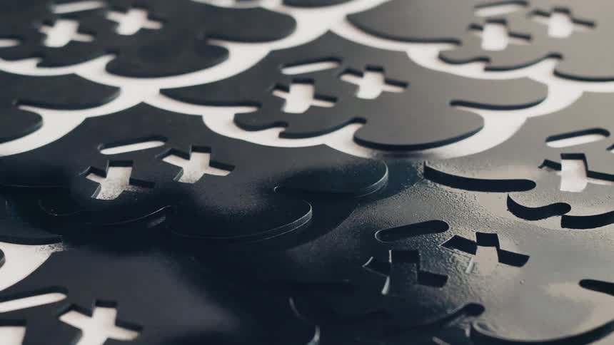 A person sprays black spray paint over and around a stencil