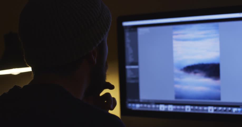 A man staring at a computer screen with his hand on his mouth