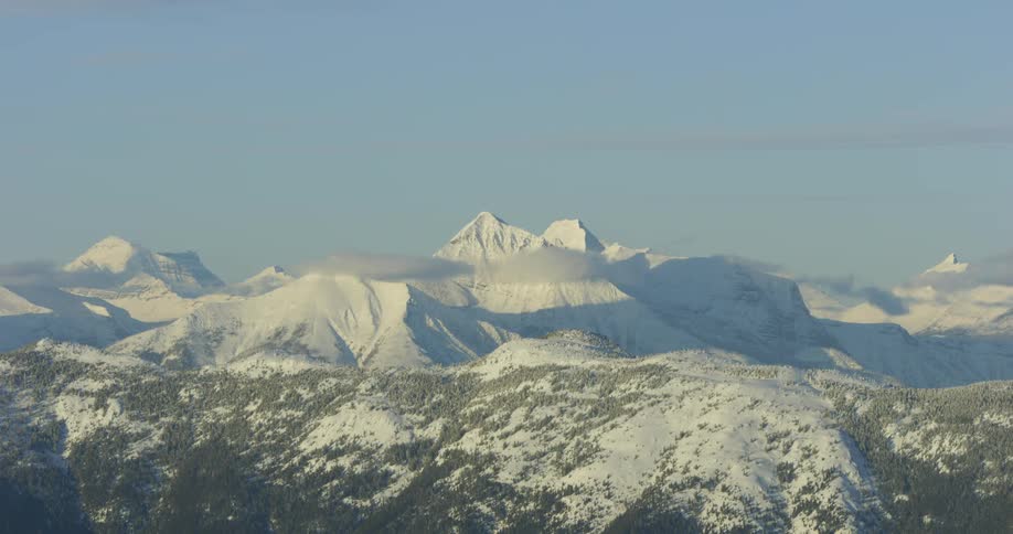 A snowy hillside leads to snow capped mountains