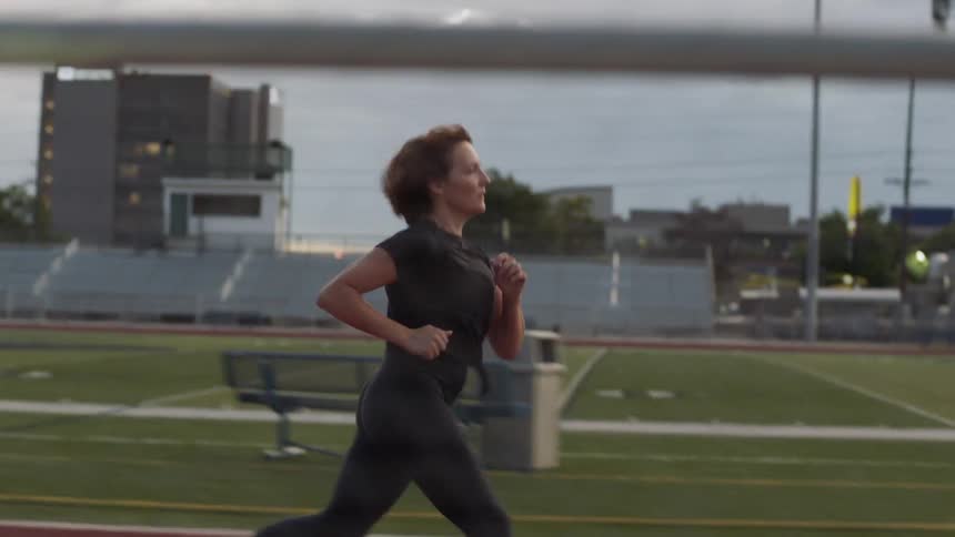 A woman is jogging outdoors on a track