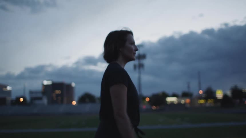 Woman walks forward under cloudy sky
