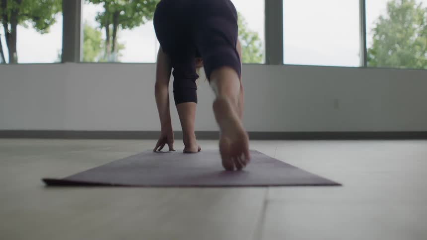 Woman steps back as she gets into a yoga pose