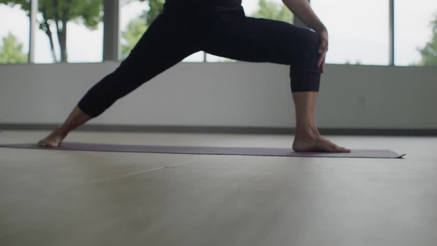 A woman does yoga on a mat in front of a window