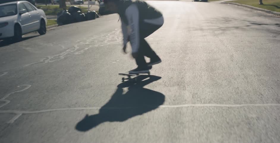 A male rides a skateboard down the center of a street and fails to land a trick on his board