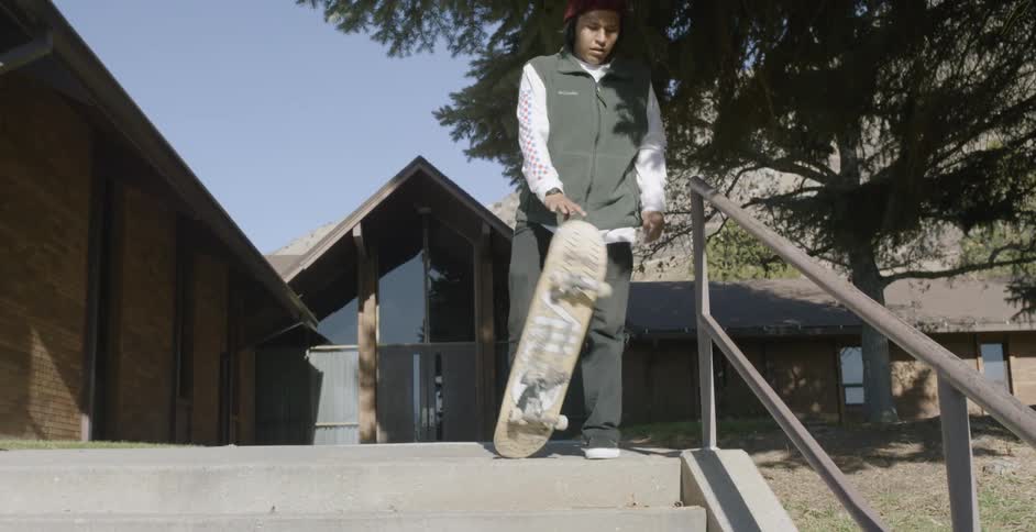 A young teen rides his skateboard to the top of some stairs