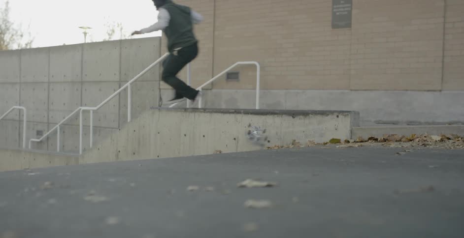 A man jumps his skateboard by the stairwell