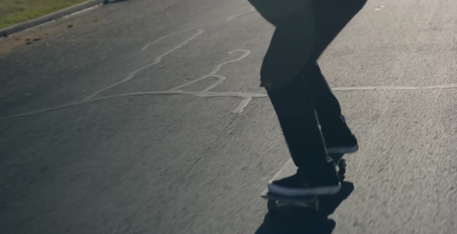 A person on a skateboard performing a trick on a black asphalt road