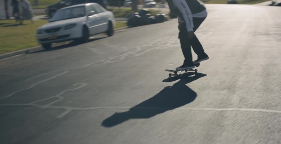A man performs a trick on a skateboard on a road on a tree lined street