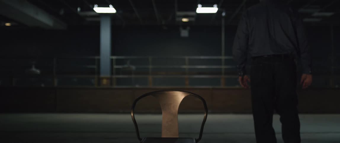 A man stands up from a chair in an empty room