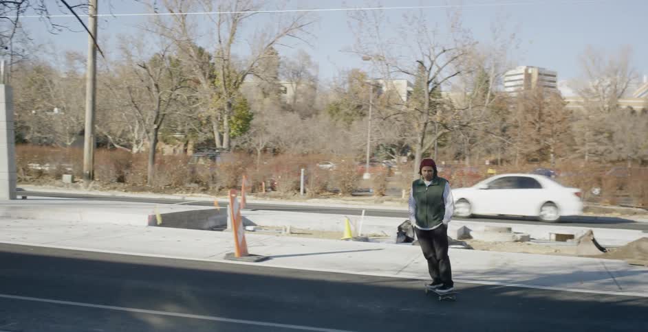 A skateboarder crossing the street from a median strip
