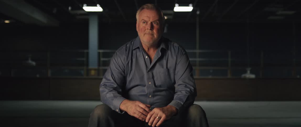 A man sits in the dark building looking around
