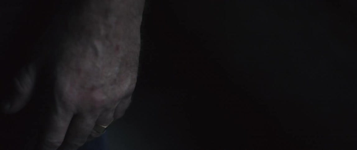 Man who wears ring stands in a dark room