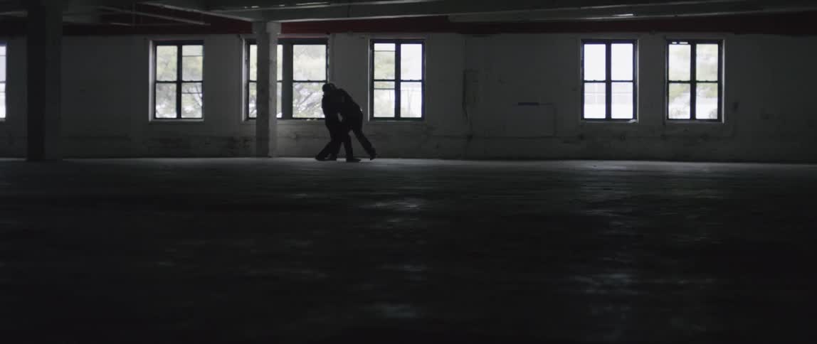 Two men fighting in a vacant building in the dark