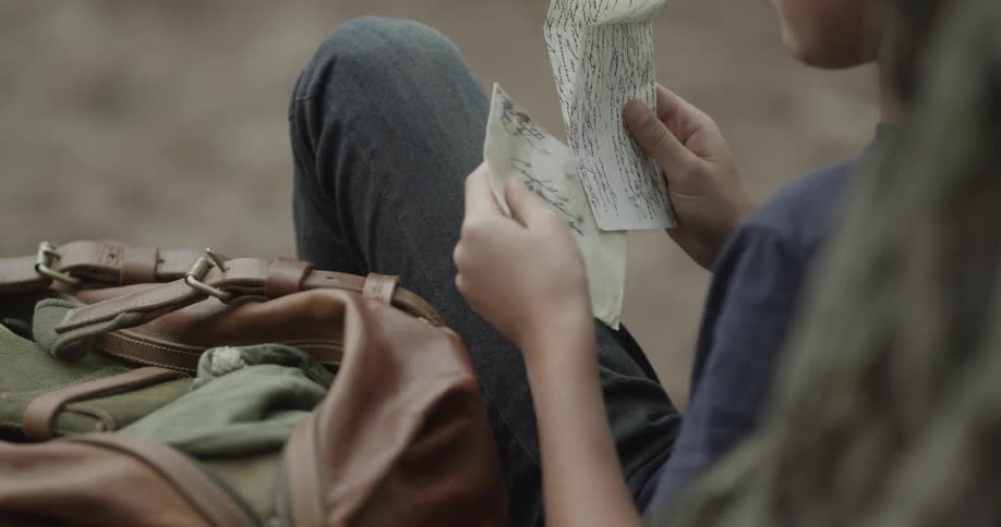 Man sitting down removes a letter from a bag