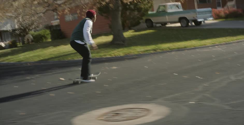 A man races on his skateboard through the neighborhood