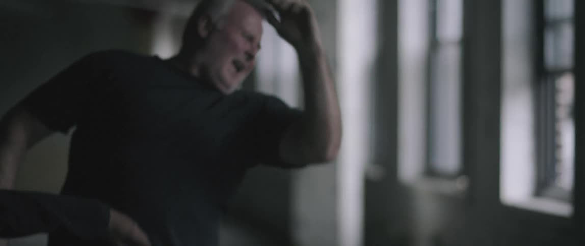 Two men fight near windows inside a building