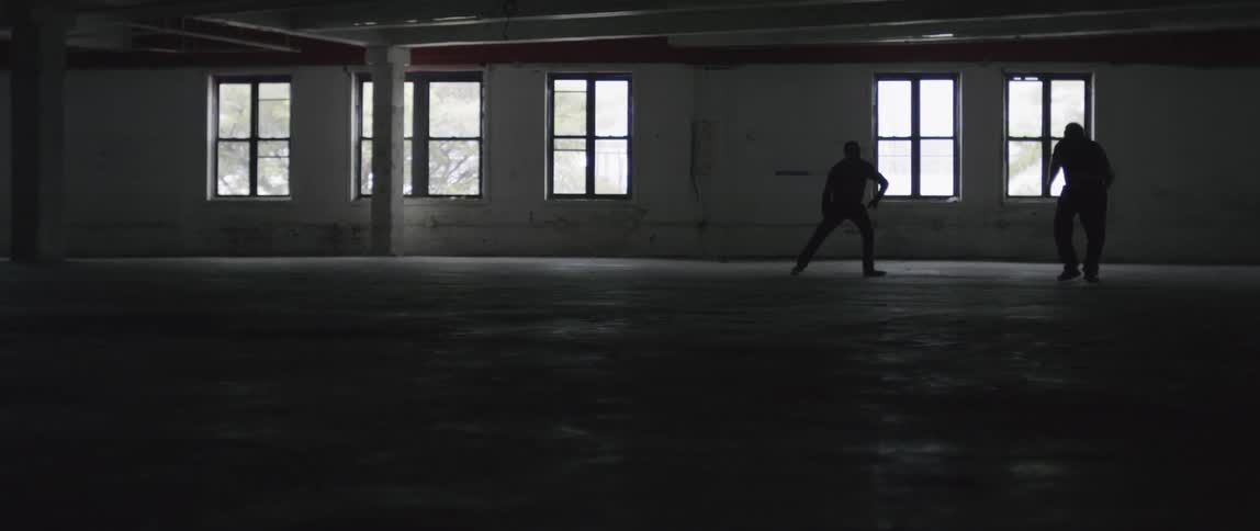Two men are having a fist fight in the dark building