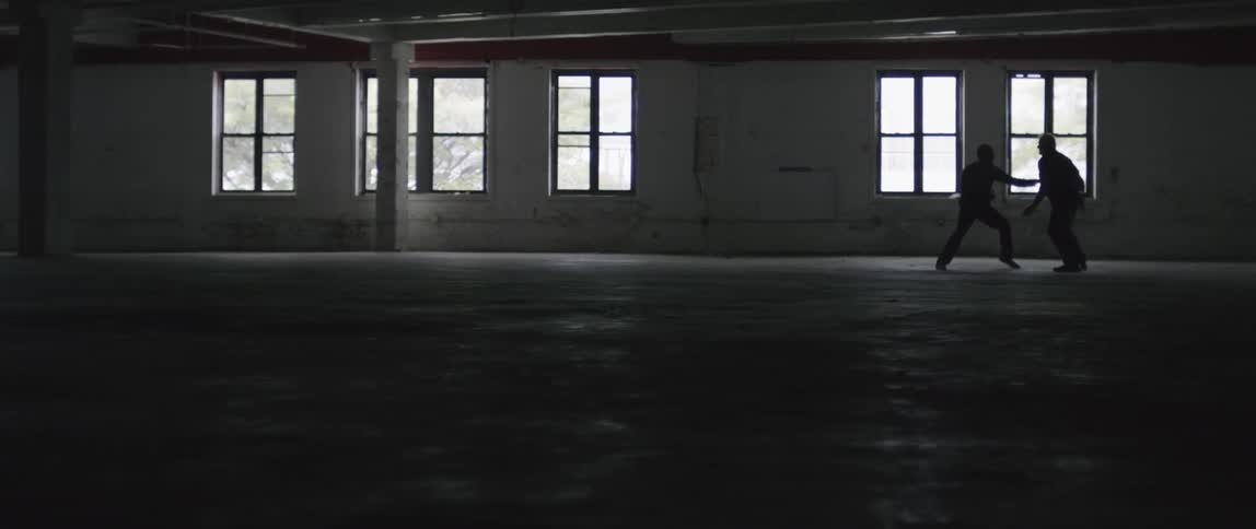 Two people fight in the dark hall