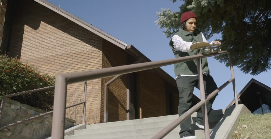 A man runs a skateboarder down a metal handrail
