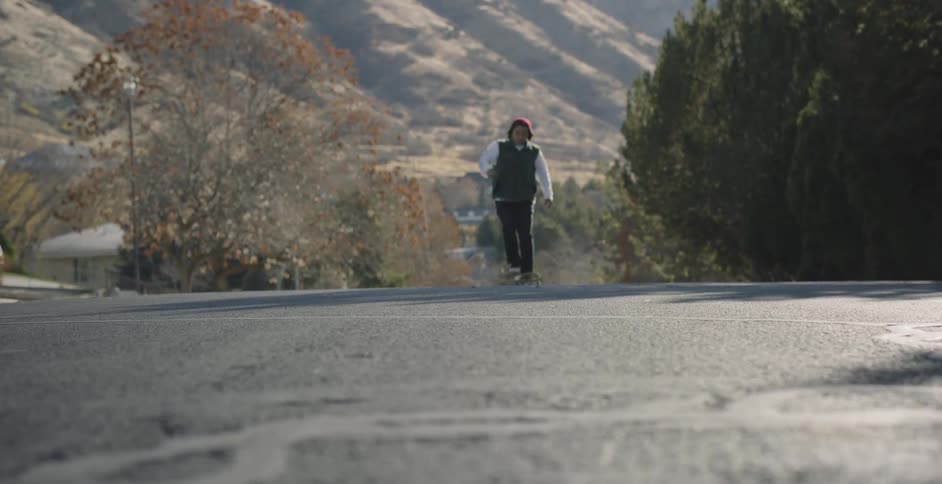 A man races by on the road with his skateboard