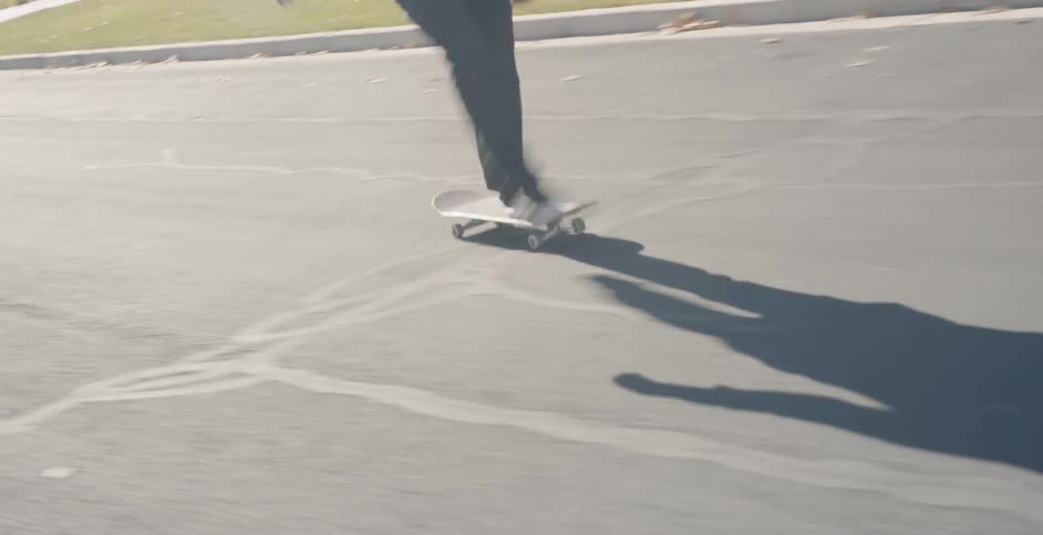 Man skateboards down a street on a sunny day