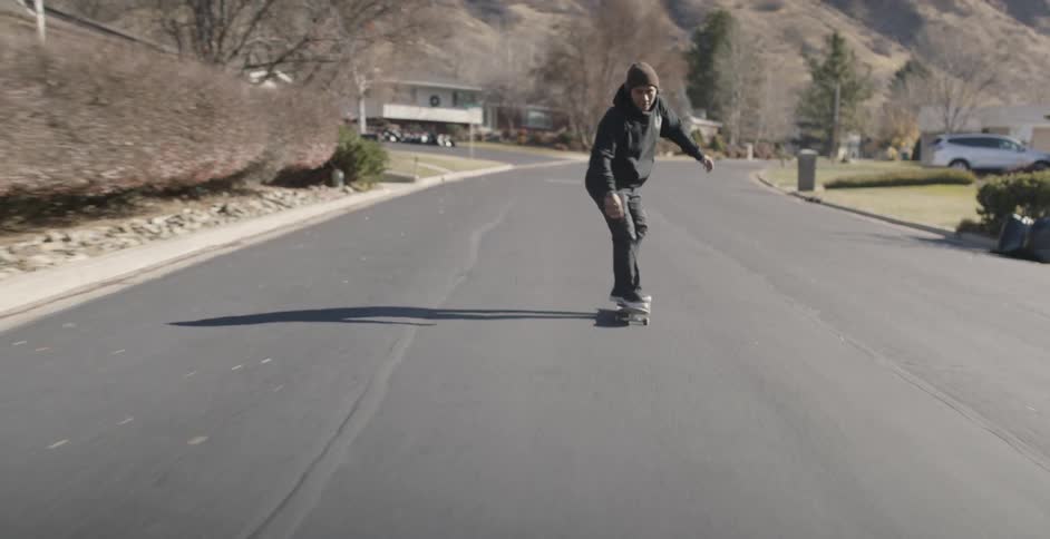 A man skateboards on a residential road