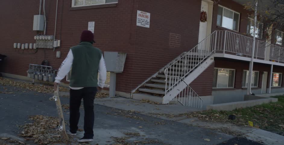 Man on skateboard rolls to a stop before stairs to climb them