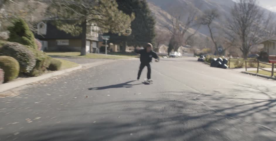 A skateboarder rides on a residential street