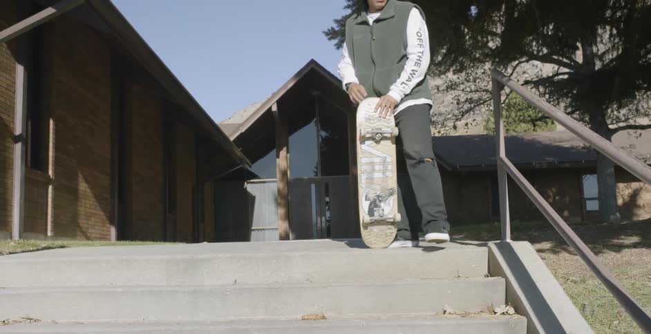 A skateboarder stops in front of concrete steps