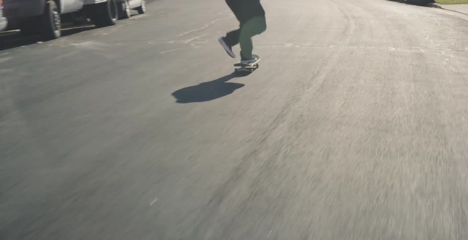 A man rides fast down the road on a skateboard