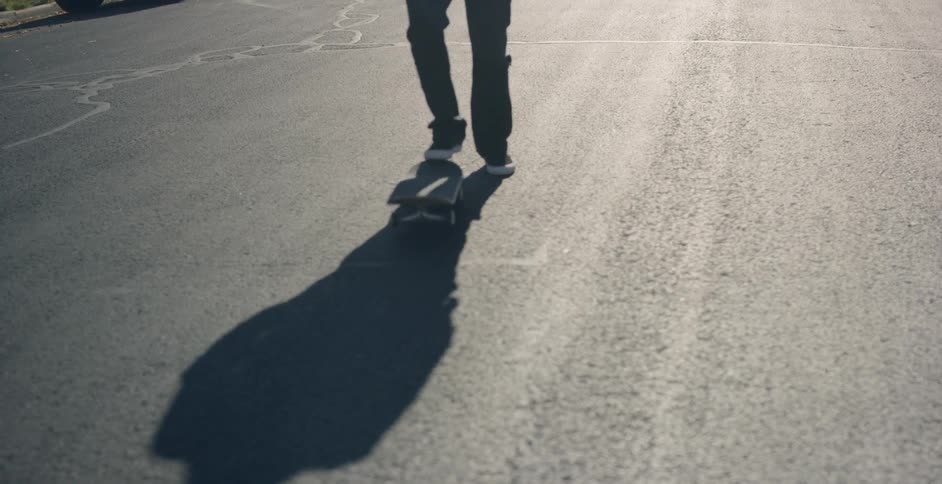 A man standing with a skateboard on a suburban street
