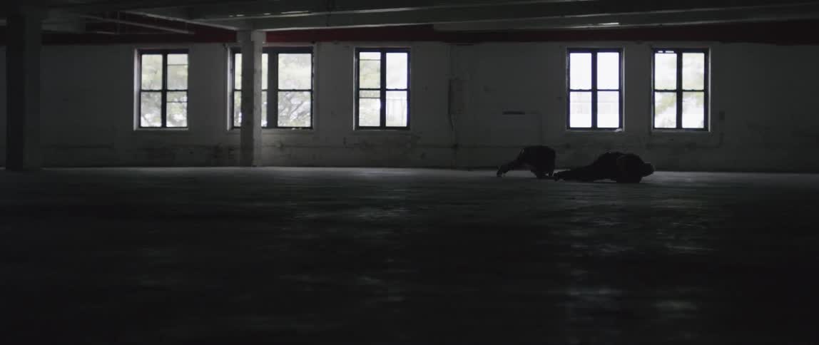 Two people roll and crawl in an empty room