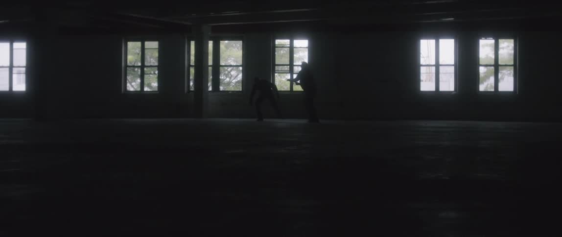 Two people are fighting in the dark building
