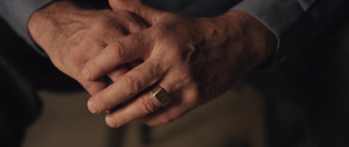 A man clasps his hands together in the room