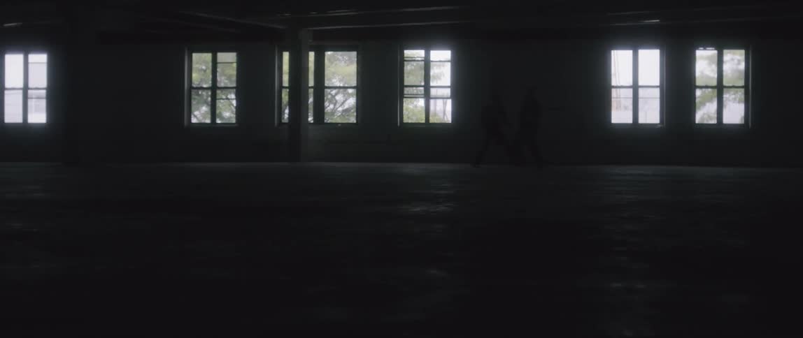 Two people fighting in a dark empty building